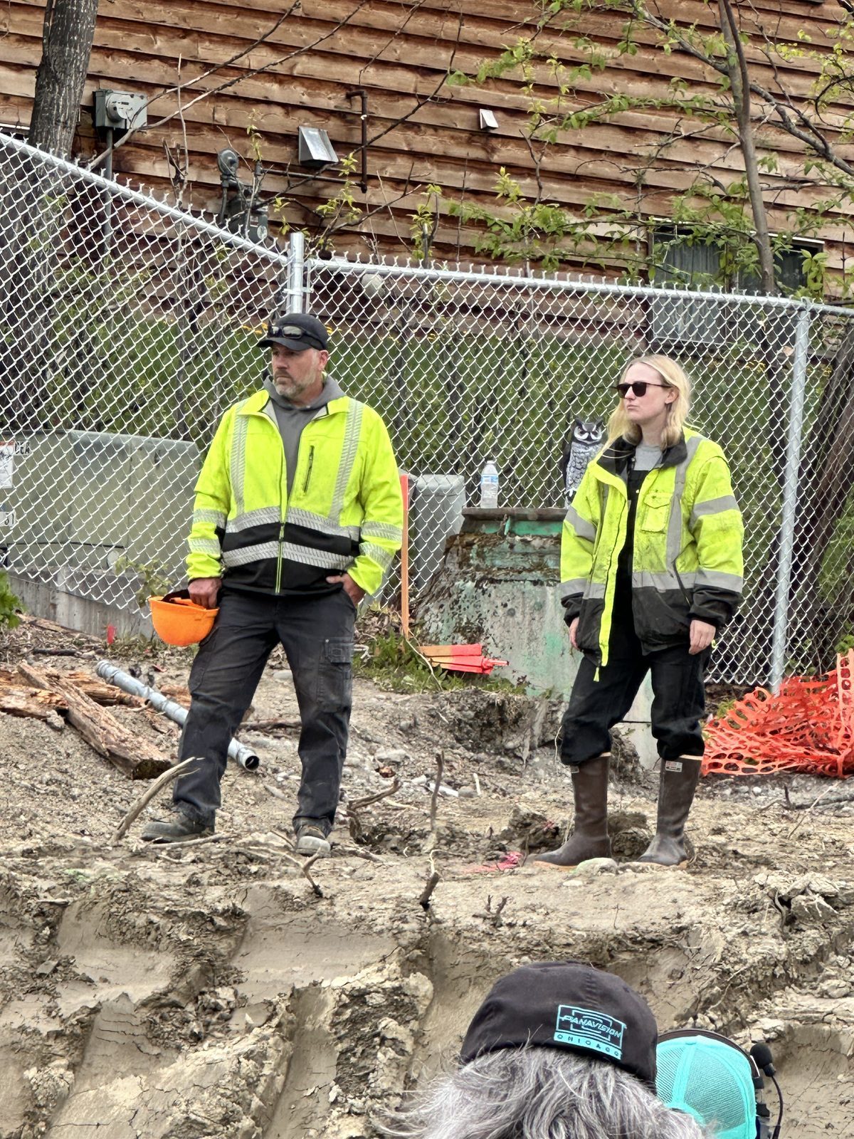 Brian Harten with actress Dakotah Fanning on the set of The Sun Never Sets film, both wearing hi-vis safety gear at an excavation site