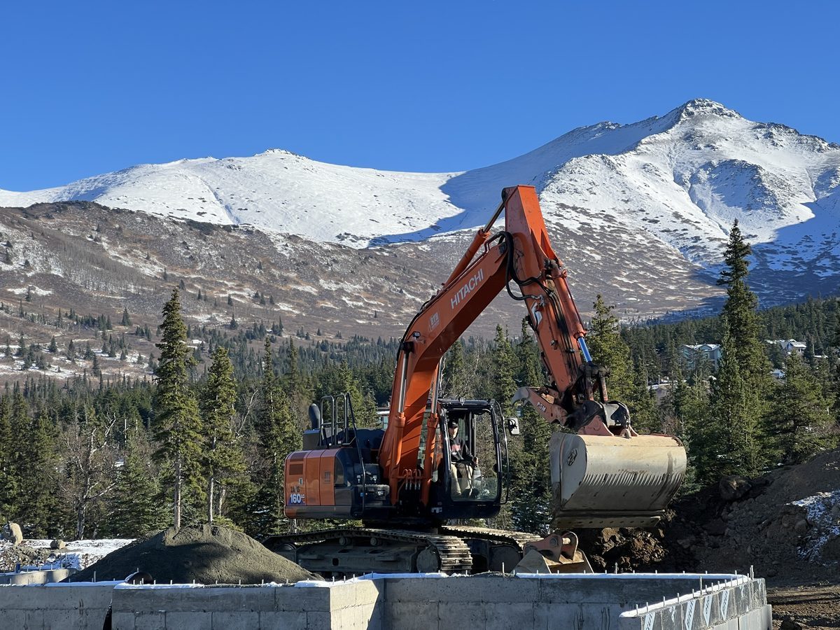 Brian Harten, owner and operator of BTH Construction, operating Hitachi excavator in front of Alaska Range mountains